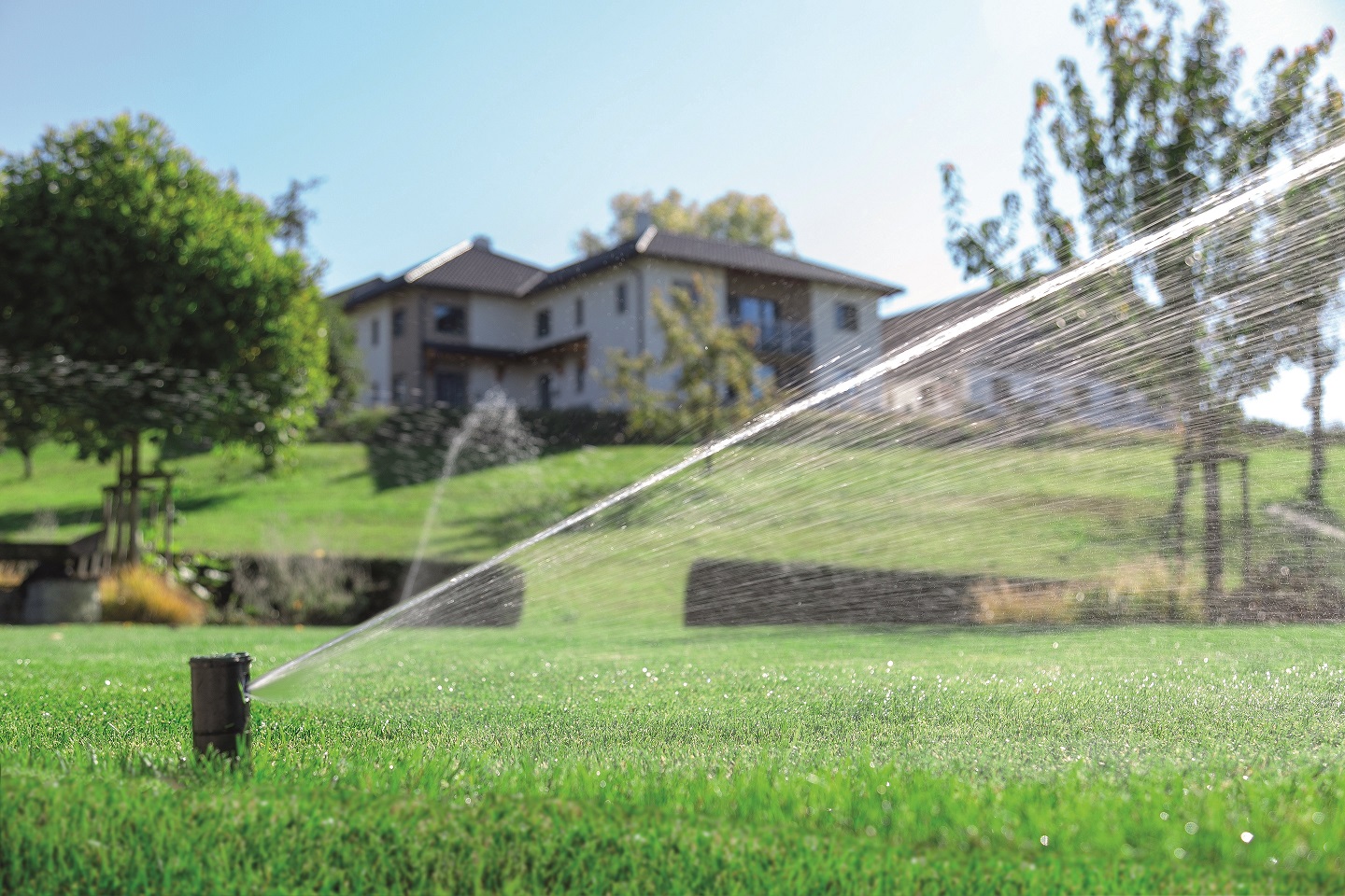 Summert smart home options: garden Loxone irrigation system in the works with a family house in the background